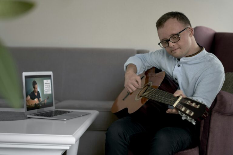 Adult caucasian man with down syndrome learning how to play at guitar