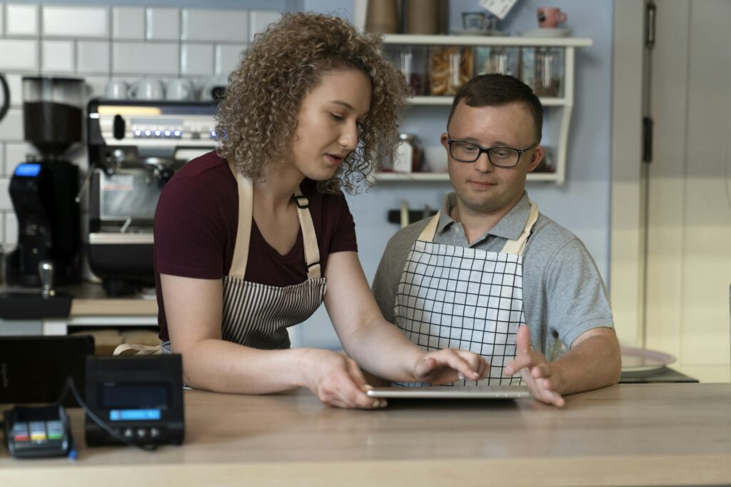 Caucasian man with down syndrome learning how to take orders on digital tablet