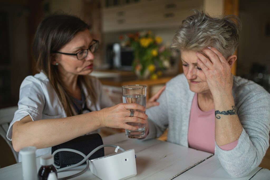 Healthcare worker or caregiver visiting senior woman indoors at home, explaining