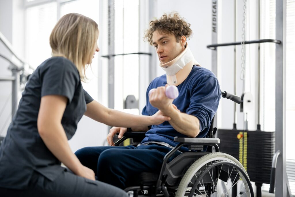 Rehabilitation specialist with guy on a wheelchair doing exercise