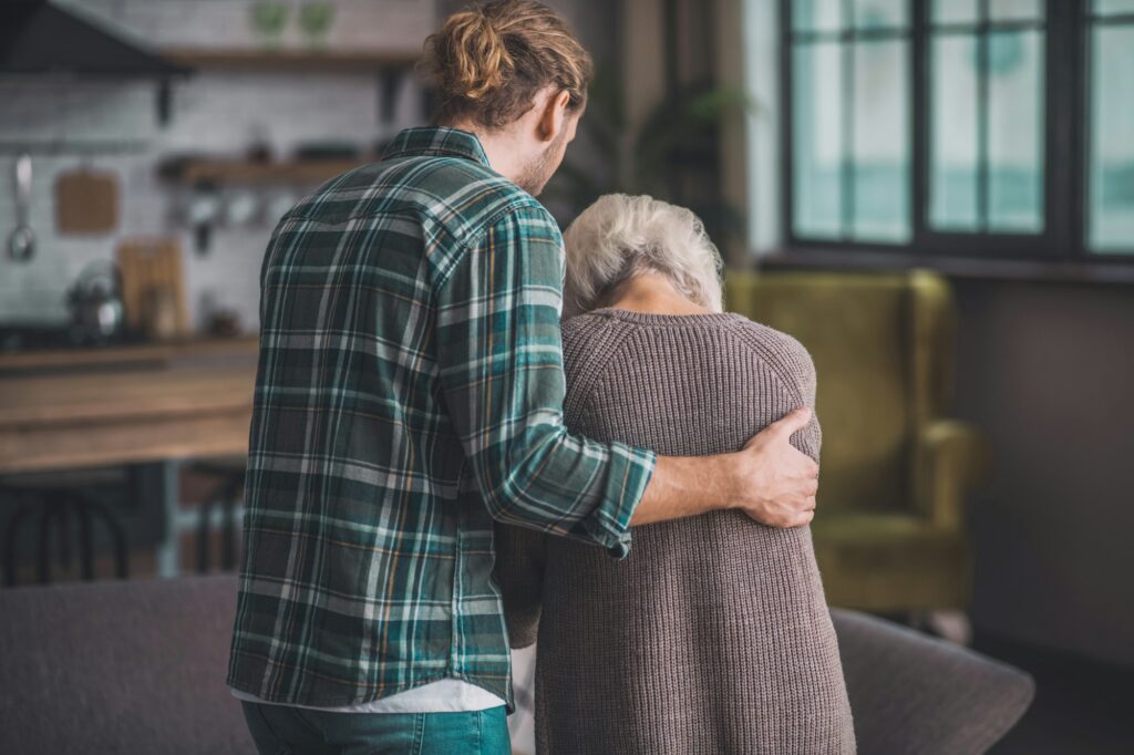 Young man in jeans supporting the old lady